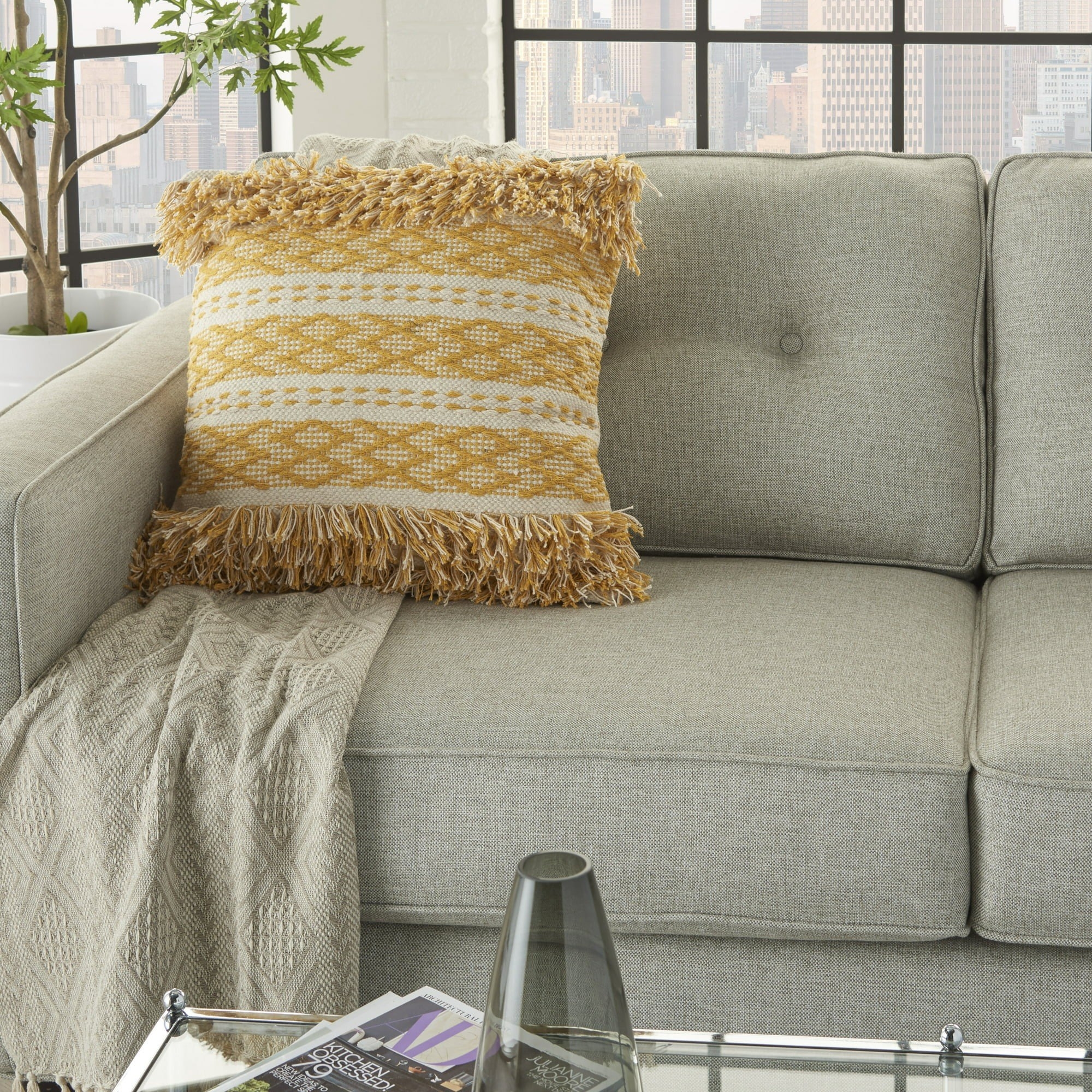 Yellow and white fringe accent pillow on beige-gray couch