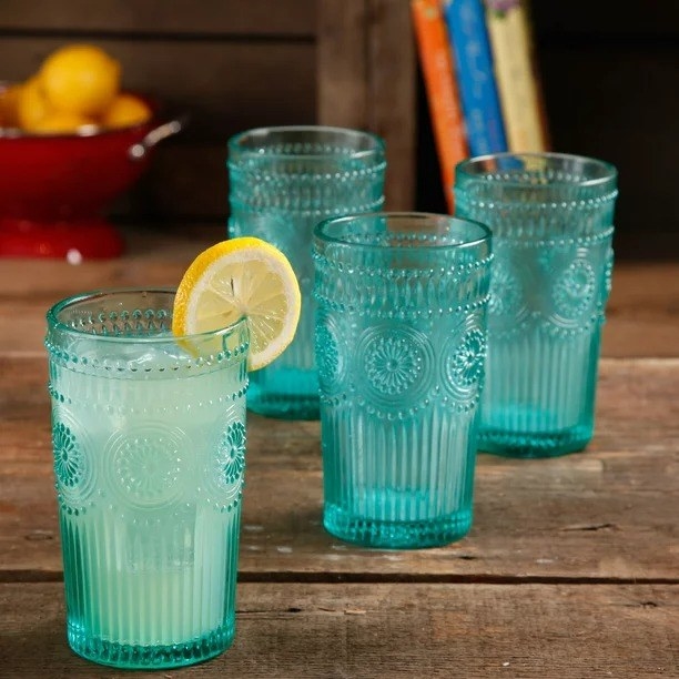 Lemonade in blue glass tumbler glass, three empty glasses behind it