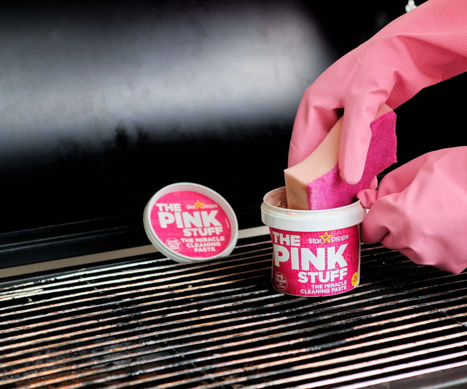 Model using the Pink Stuff on a grill with a sponge