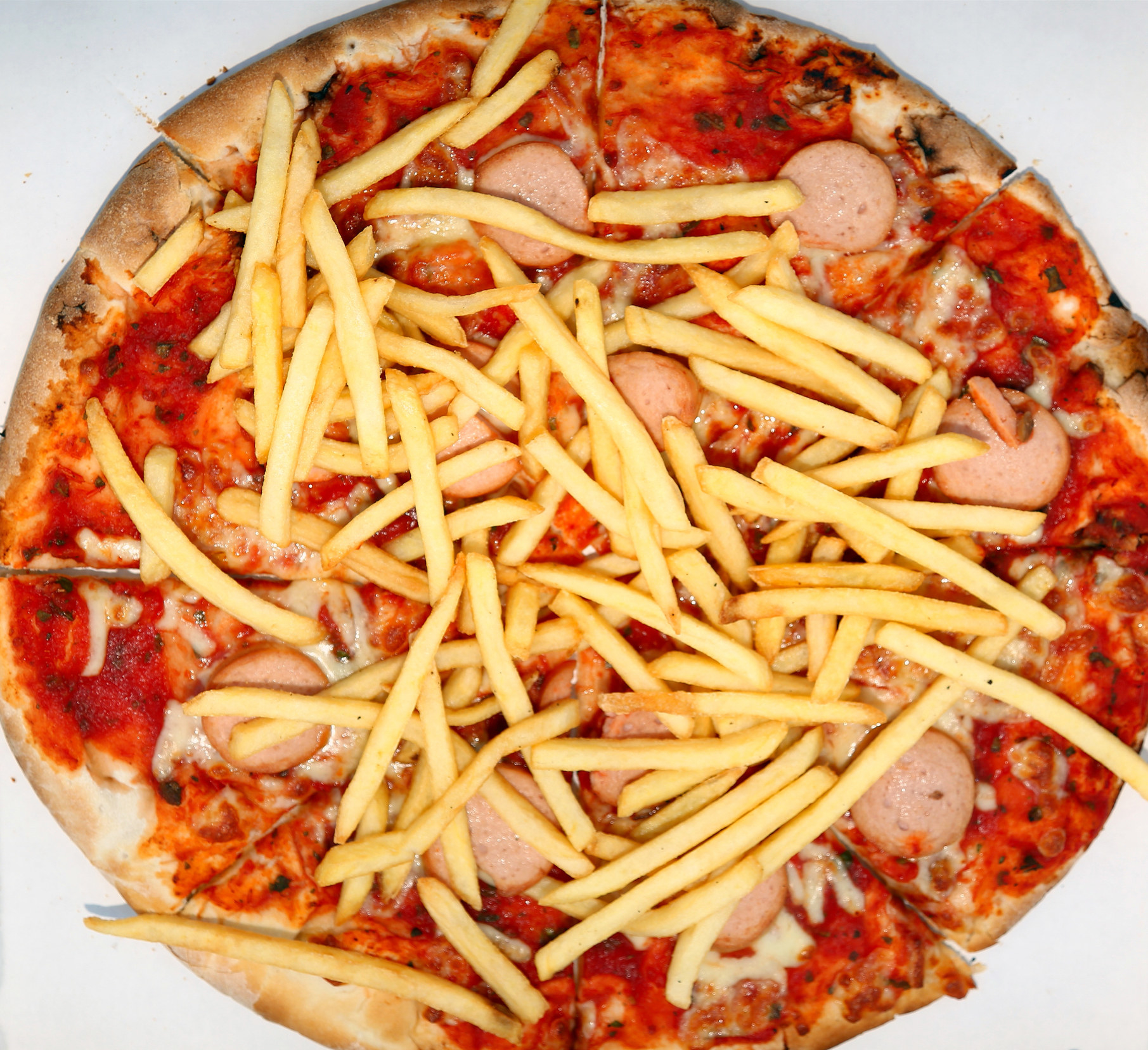 Pizza with fries and sliced hot dogs.