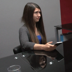 A woman shaking her head and looking at her phone