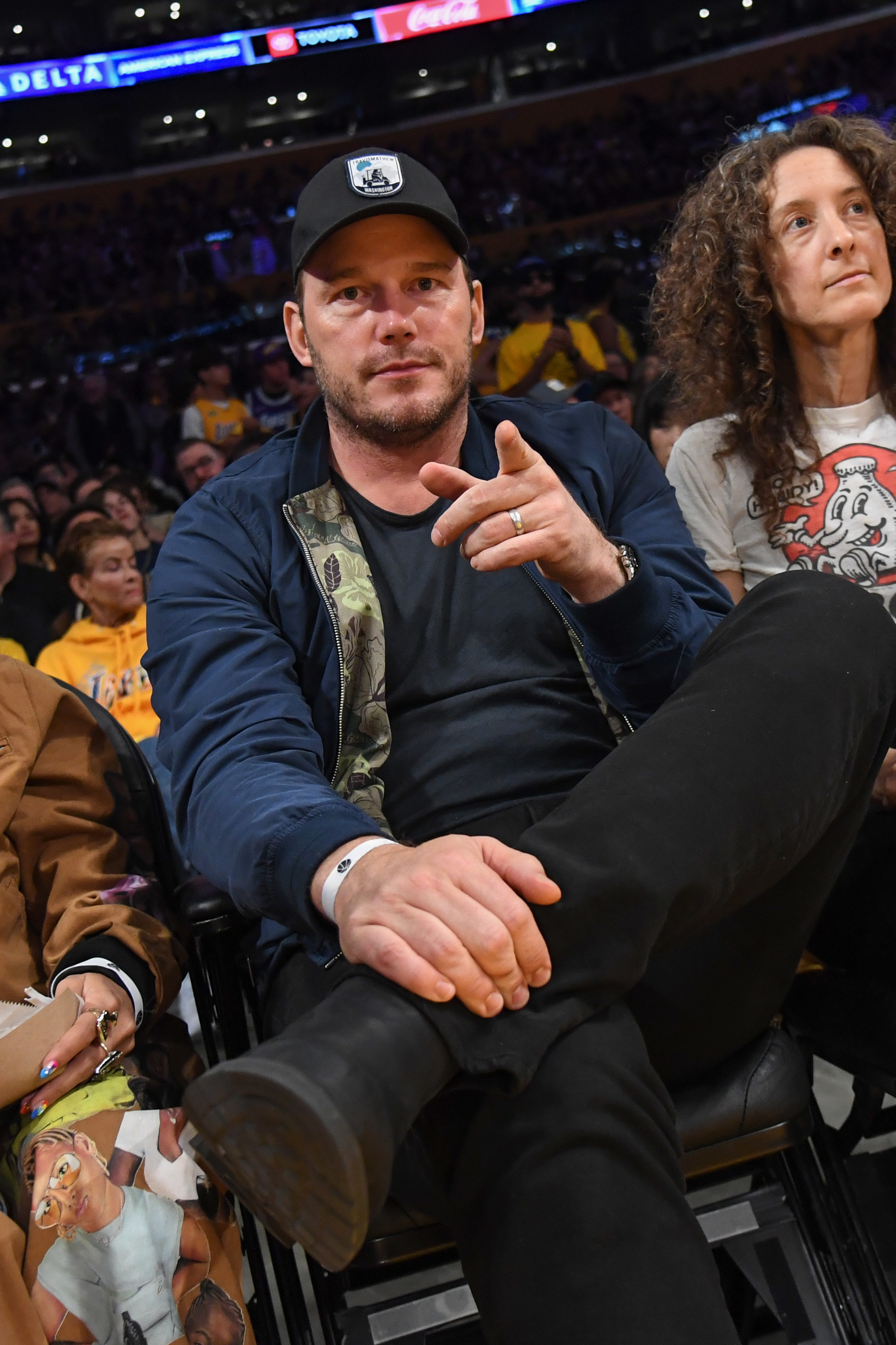 A closeup of Chris Pratt sitting court-side and pointing his finger at the camera