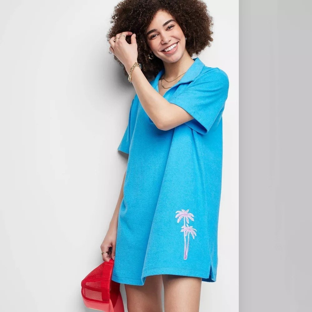 A model in the bright blue dress with pink embroidered palm trees