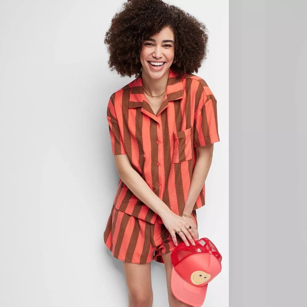 A model in the brown and coral striped shirt and shorts set