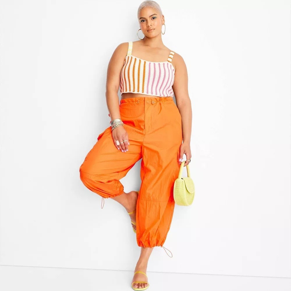 A model in the orange ankle pants