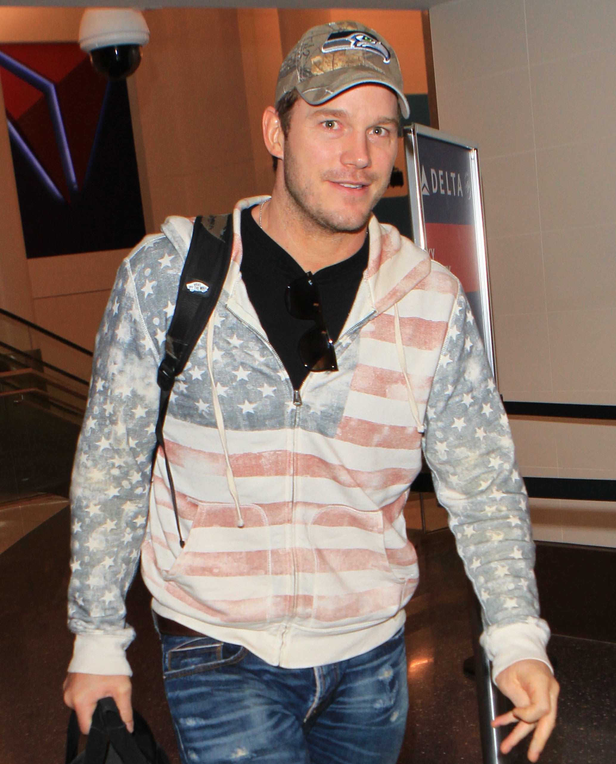 Chris in a cap, US flag hoodie, and jeans