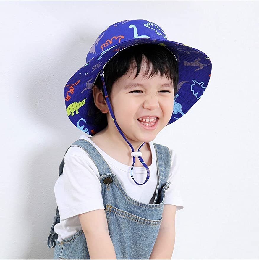 Child model wearing dinosaur themed bucket hat