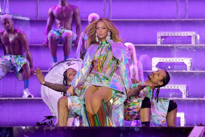 Beyoncé onstage as two dancers bend over backwards behind her
