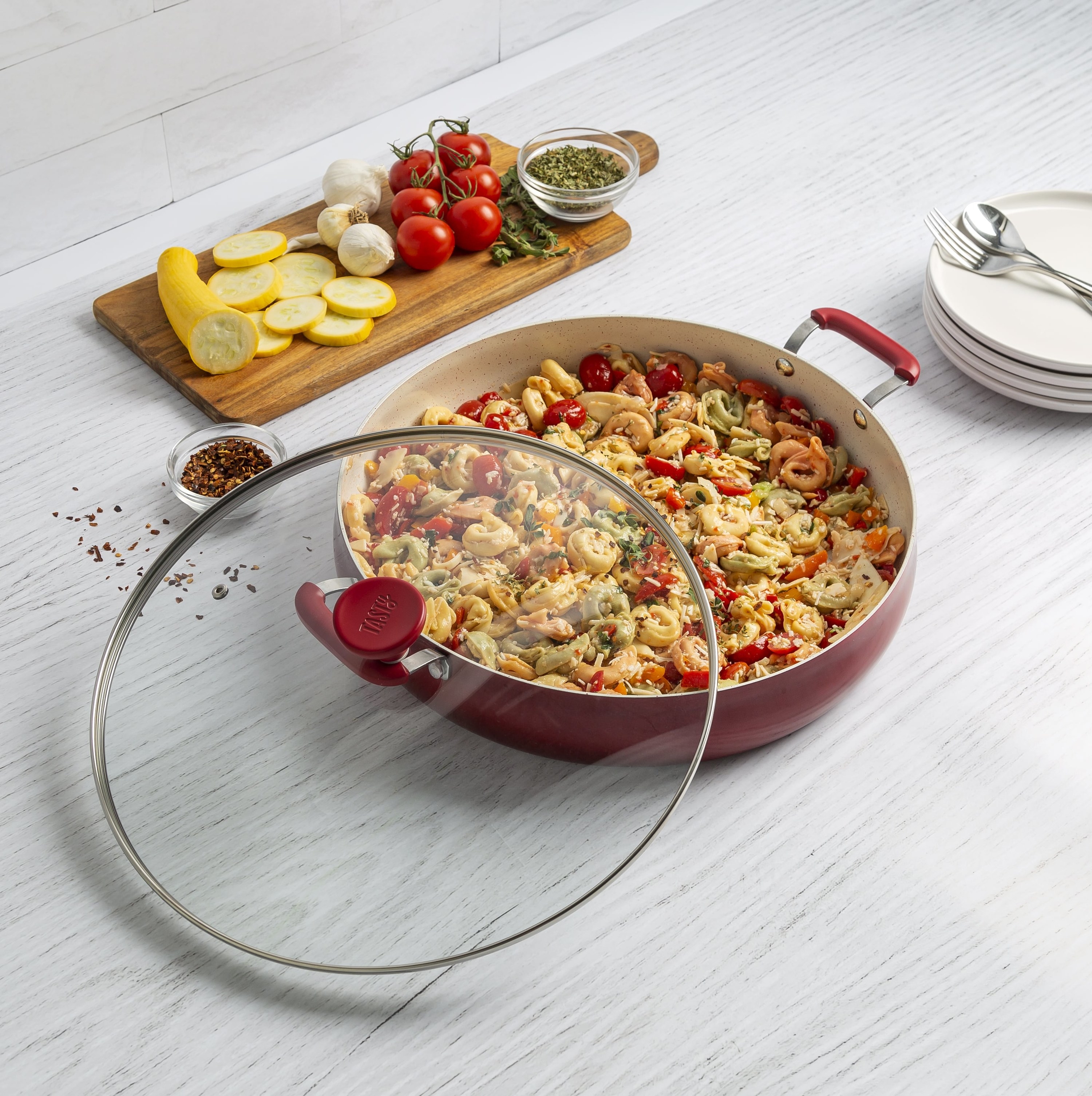 Tasty Red Centerpiece Pan displayed with pasta and serving board with vegetables