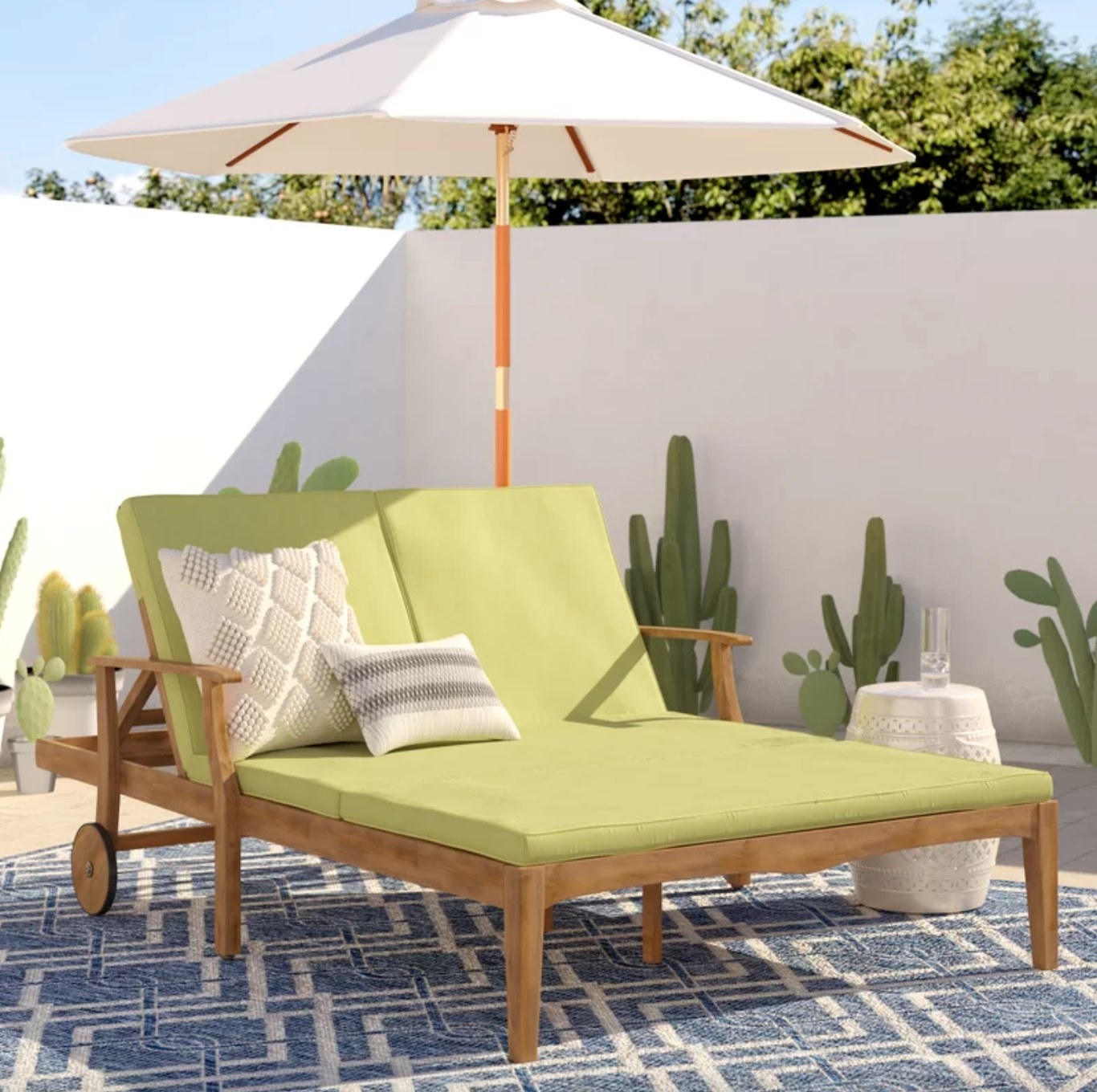 the light wood double chaise with a green frame and decorative pillows in a decorated outdoor space