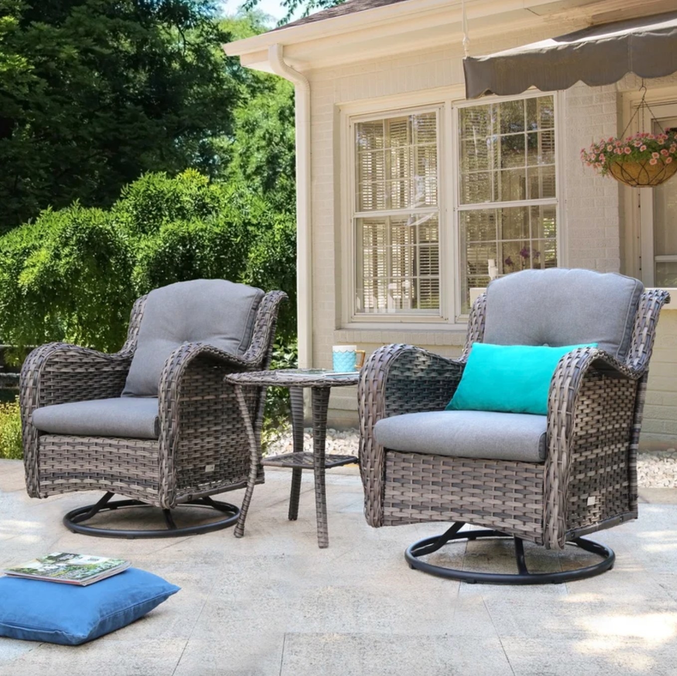the heavily cushioned grey wicker chairs and side table in a decorated patio space
