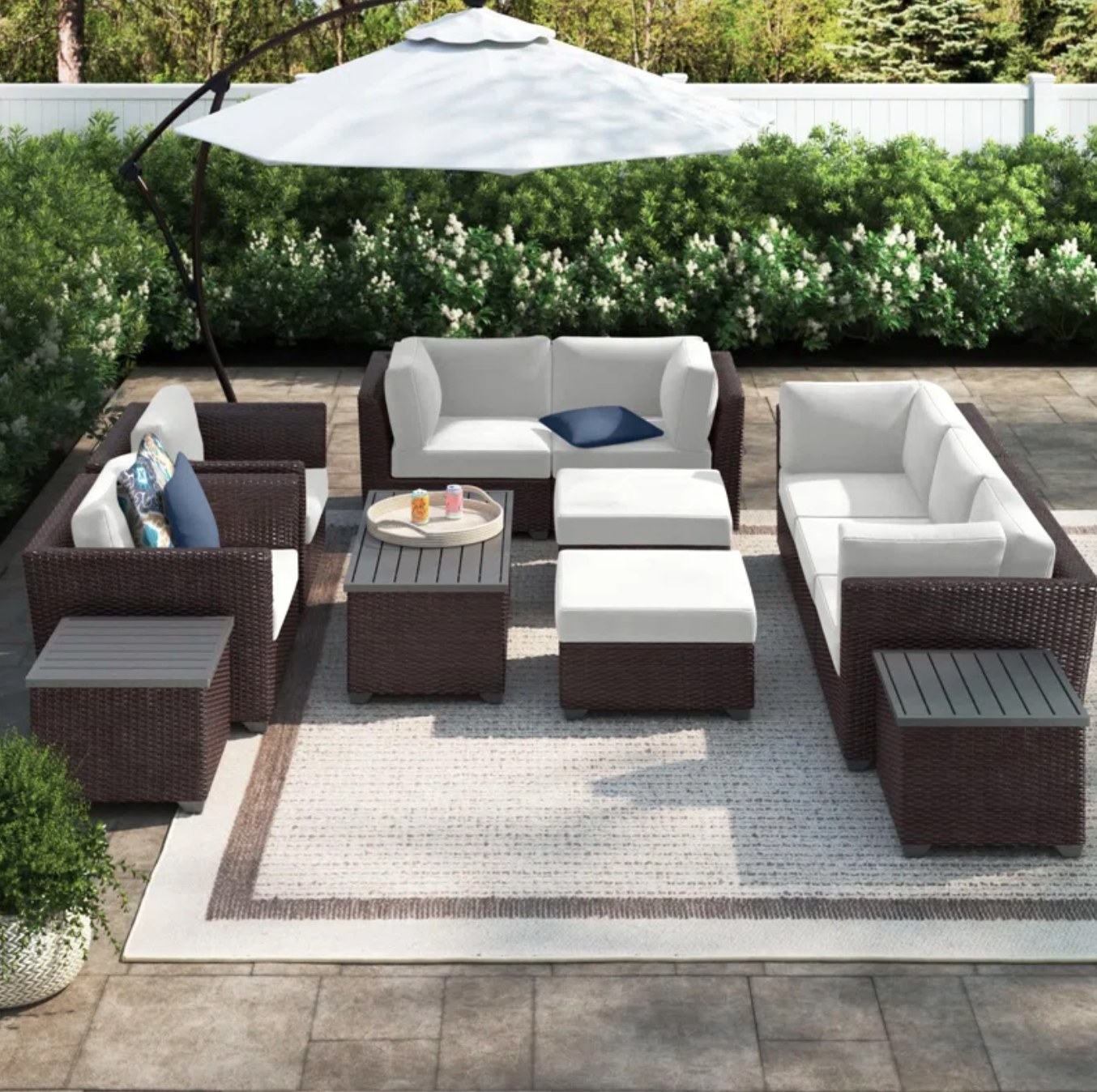 the dark wood and light cushioned set on a light outdoor rug with a matching umbrella