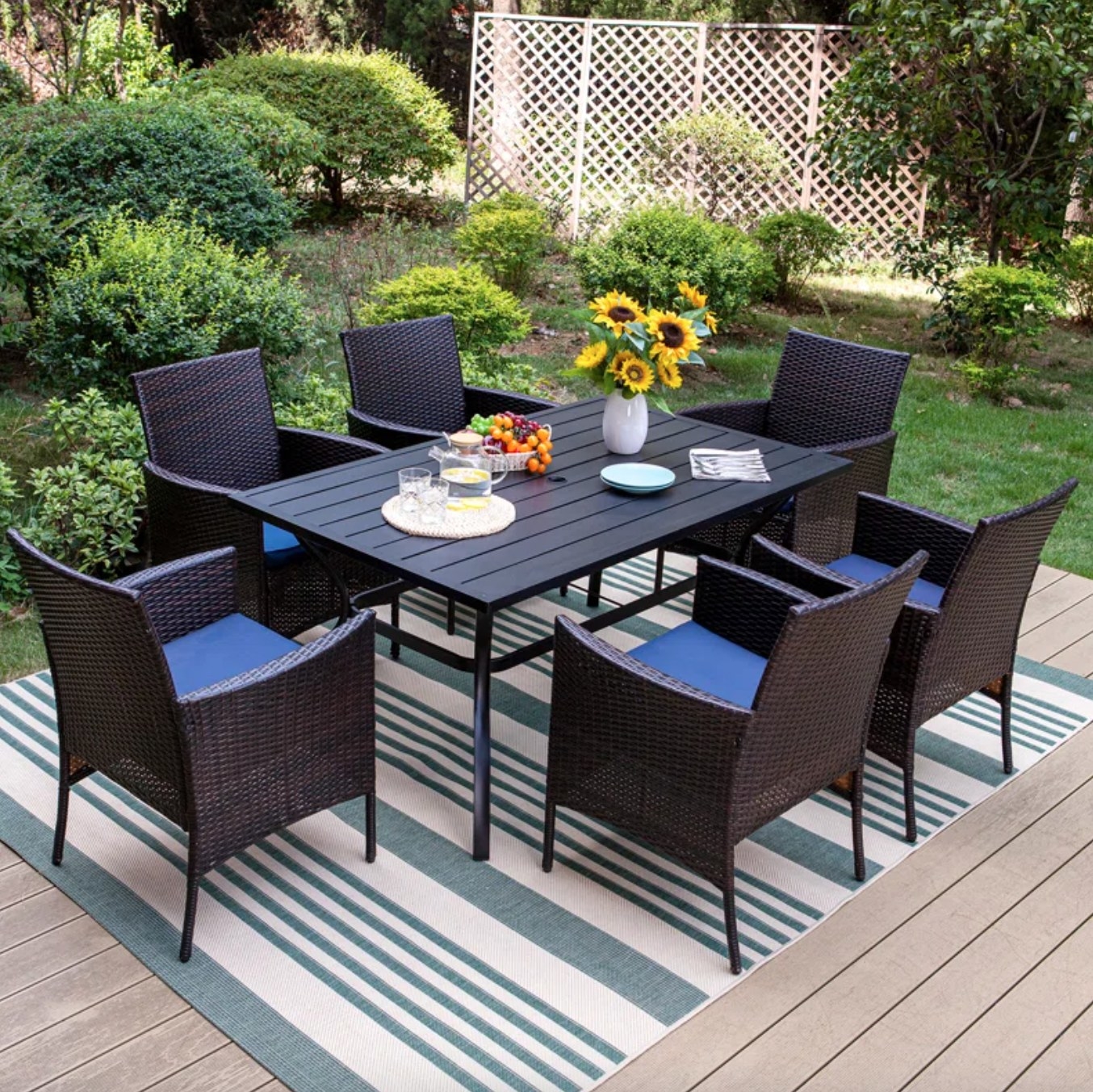 the large black metal table with six black chars with blue cushions in a decorated outdoor space