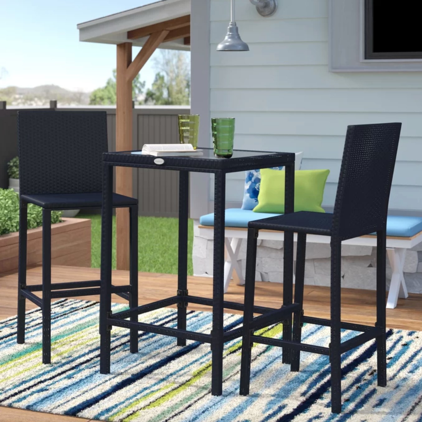 the black tall table and chairs on a striped rug in a decorated outdoor space