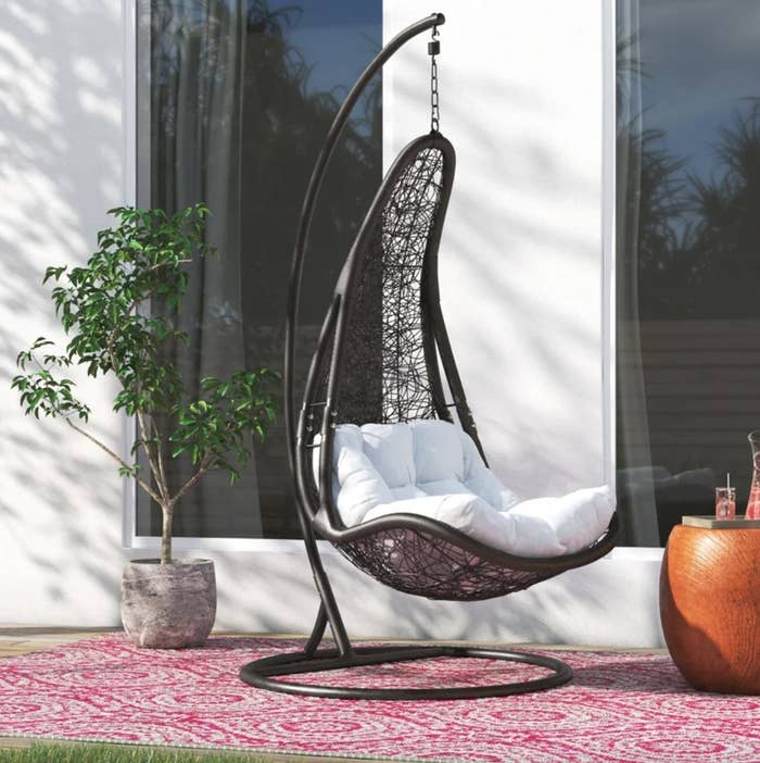 the grey hanging chair with a white cushion in a decorated outdoor space
