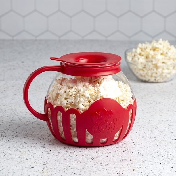 Red popcorn maker, bowl of popcorn in the background