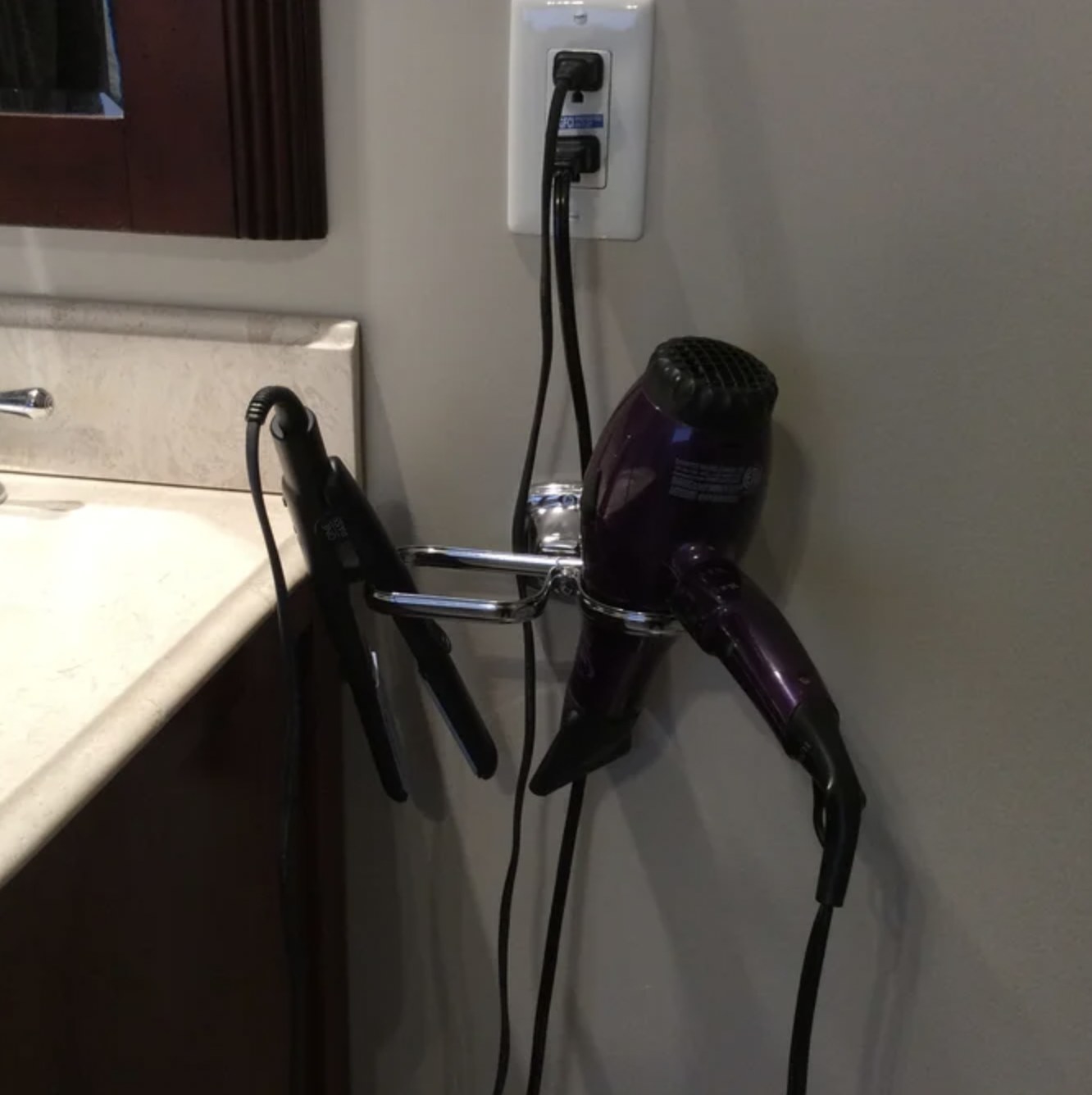 Reviewer's hair dryer and straightener in the silver holder on wall by counter