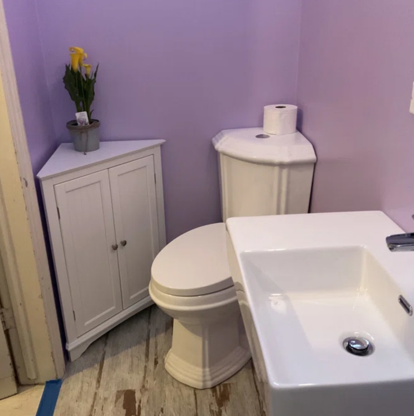 the white mid-height cabinet tucked into corner besides toilet