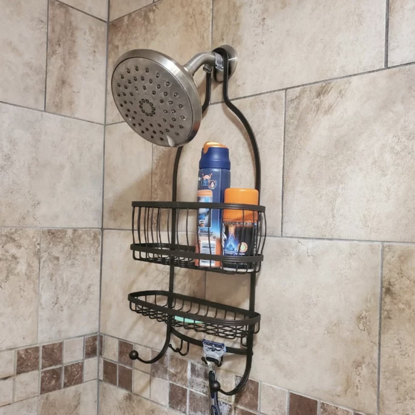 Reviewer's black caddy hanging from showerhead with razor supplies in it
