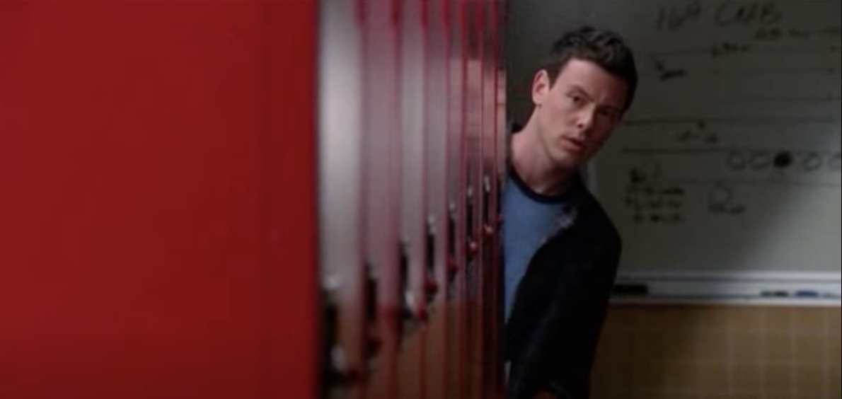 Finn looking around the corner of a set of lockers