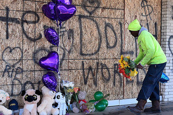 A man places flowers at the memorial for Young Dolph outside of Makeda's Cookies bakery