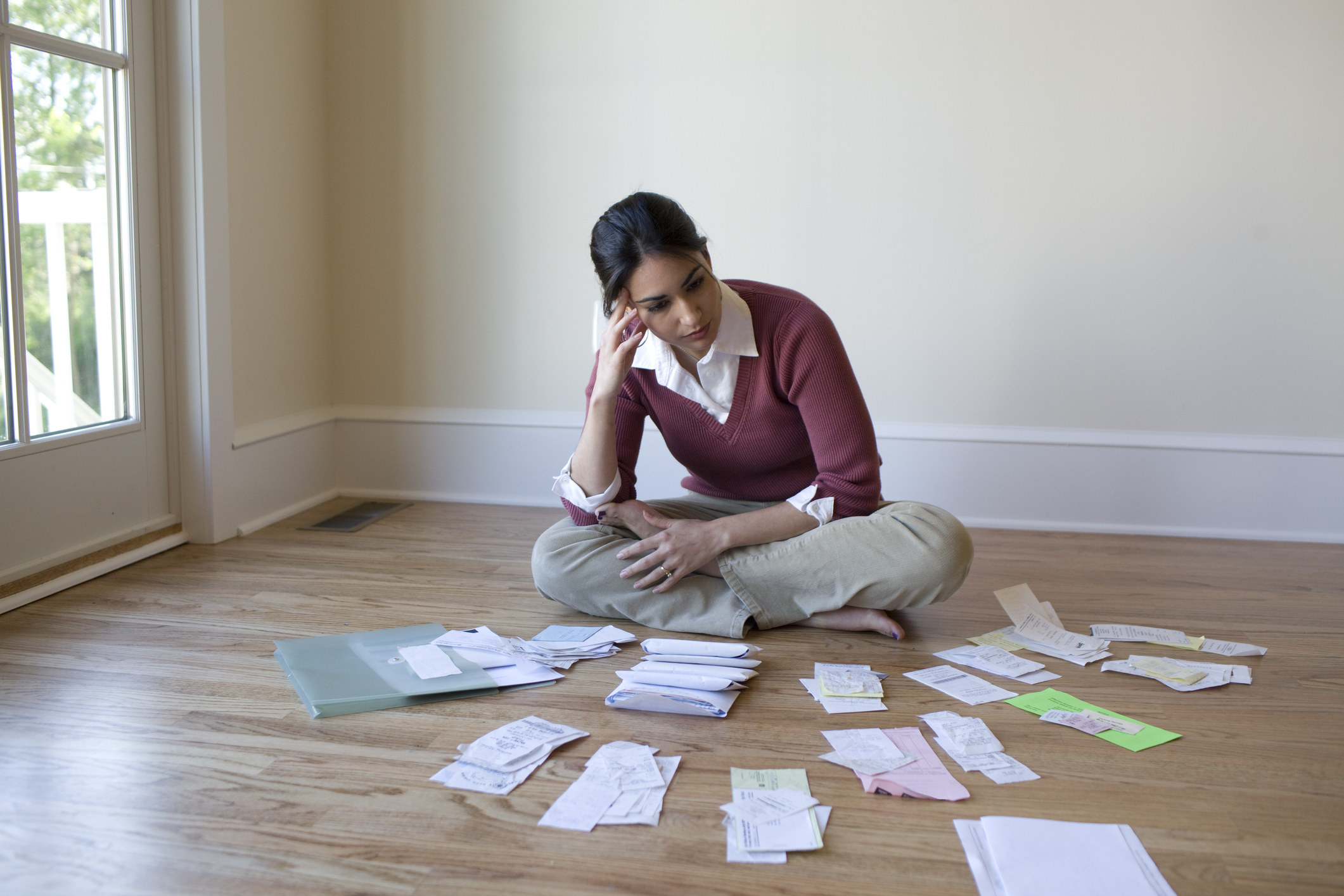 A woman sitting on the floor surrounded by paperwork