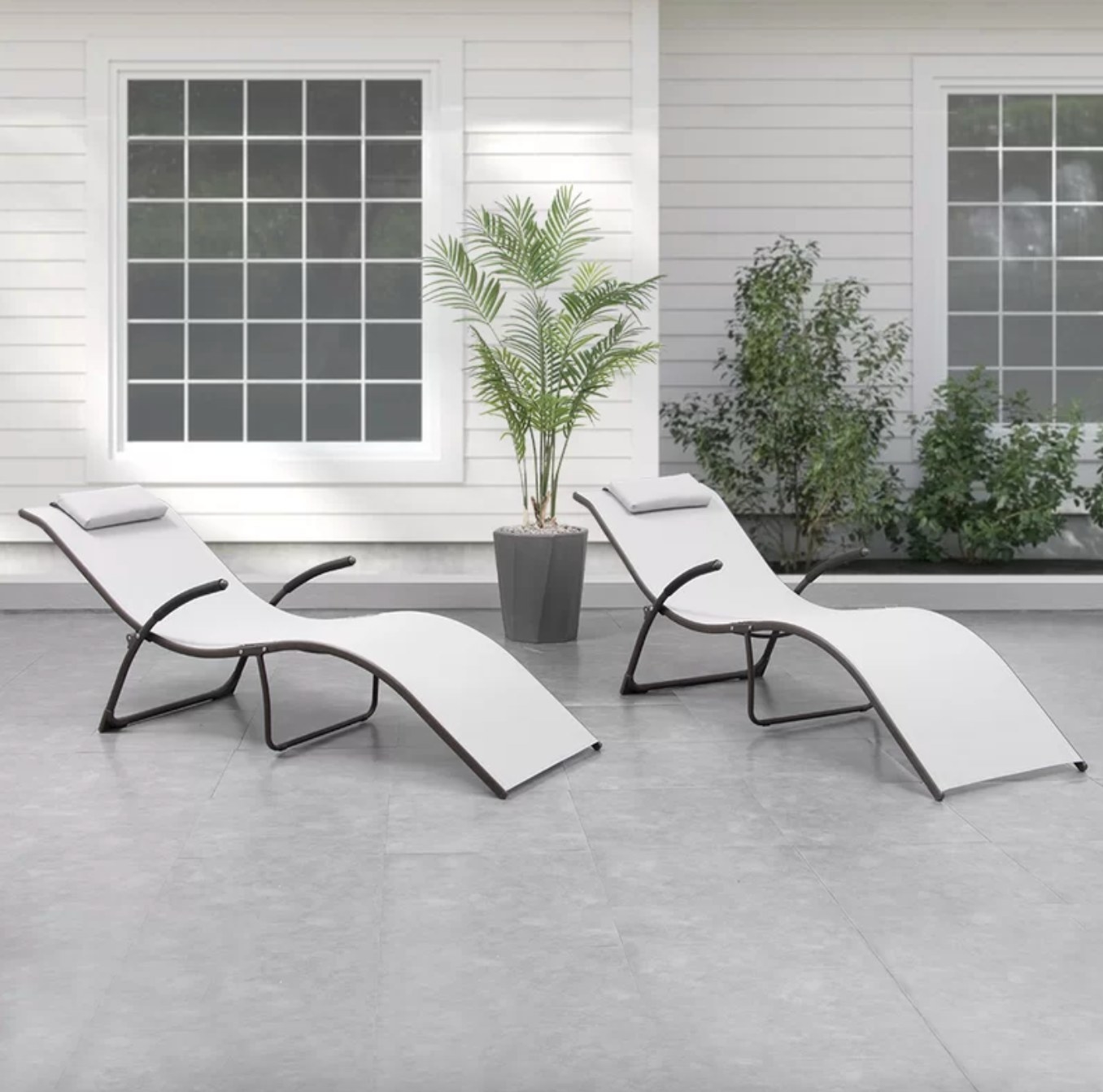 the light grey swoopy shaped chaises in a decorated outdoor space