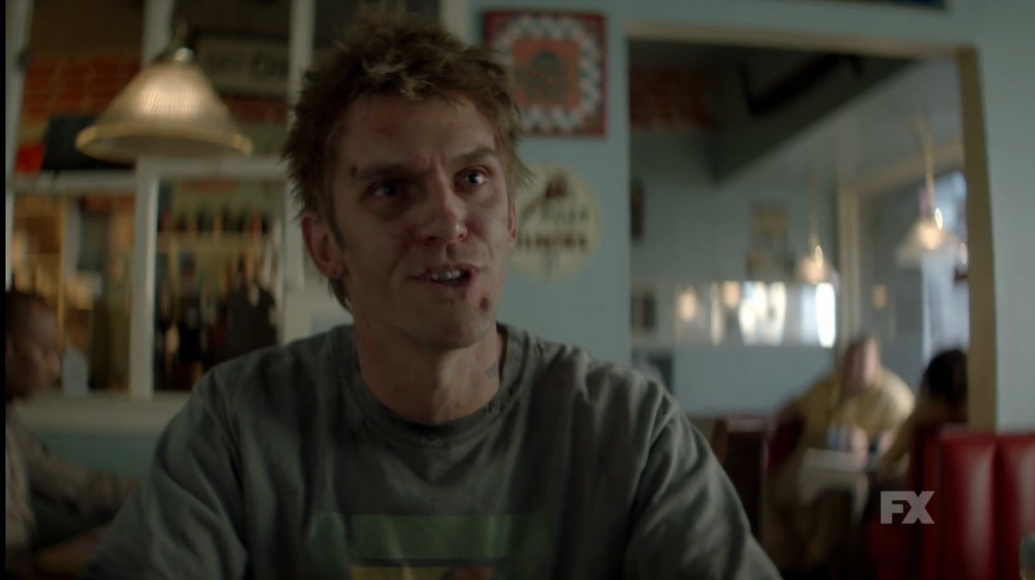 Dan Stevens, in a haggard visage, attempts to have a conversation in a restaurant