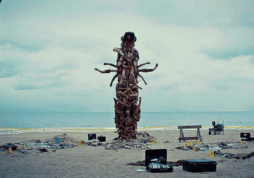 A crime scene by a beach exposes a totem pole made from human body parts.