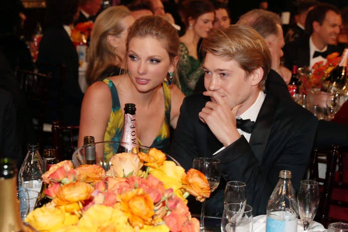 Taylor and Joe sitting at a table with a bottle of champagne in front of them