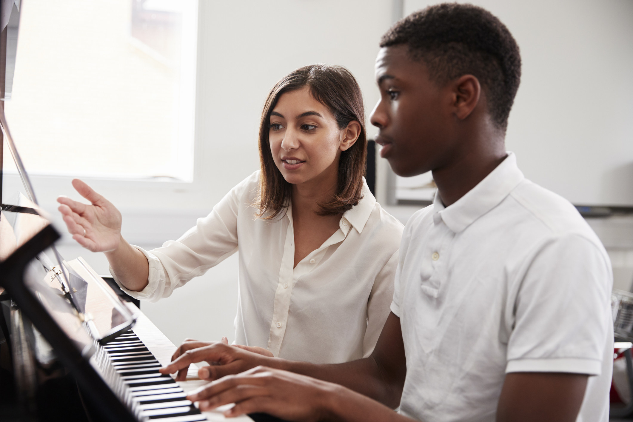 Teacher guiding a student at a piano