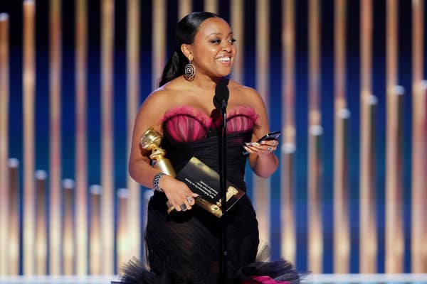 Quinta onstage holding an award