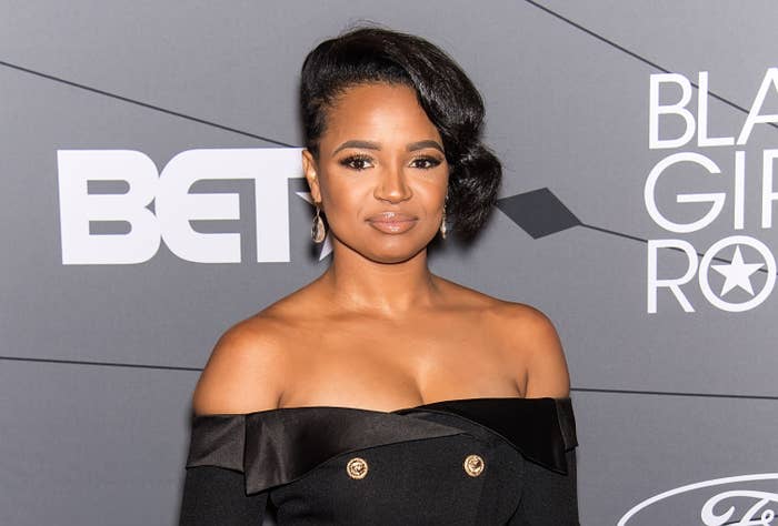 A closeup of Kyla Pratt wearing an off-the shoulder outfit with large buttons