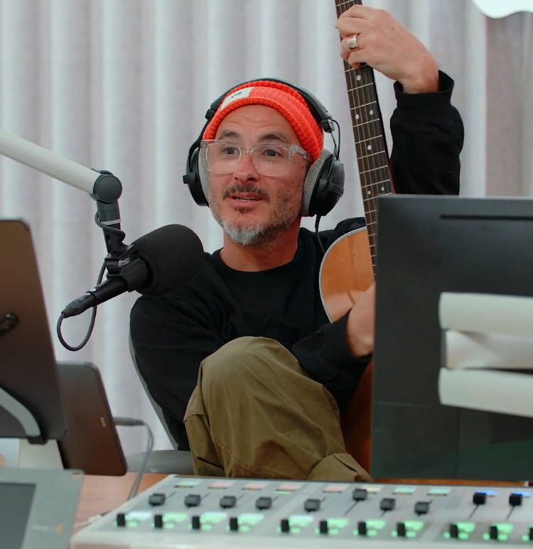 A closeup of Zane Lowe holding a guitar while conducting an interview