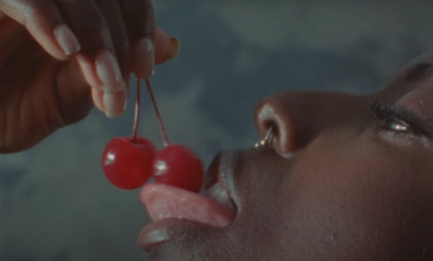 Someone licking two cherries
