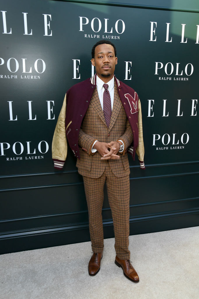 wearing a plaid suit with a letterman over his shoulders