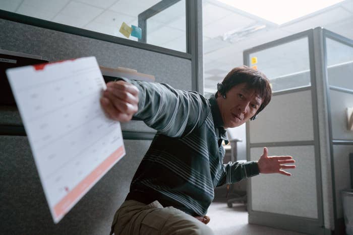 in the movie crouching down holding an evelope in an office