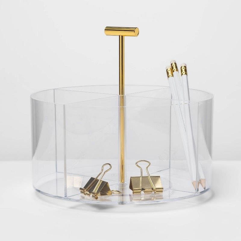 a desktop organizer with three white pencils and gold paper clips