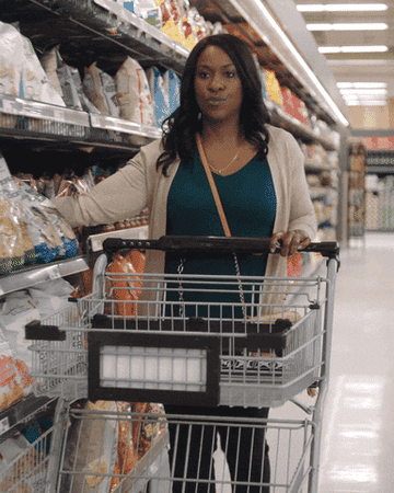 Woman putting bags of potato-chips in shopping cart