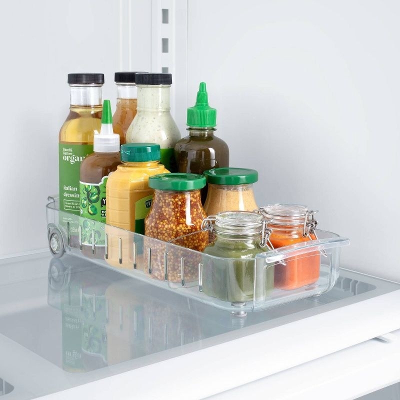 a roll out fridge caddy holding different bottles of sauces and dressings