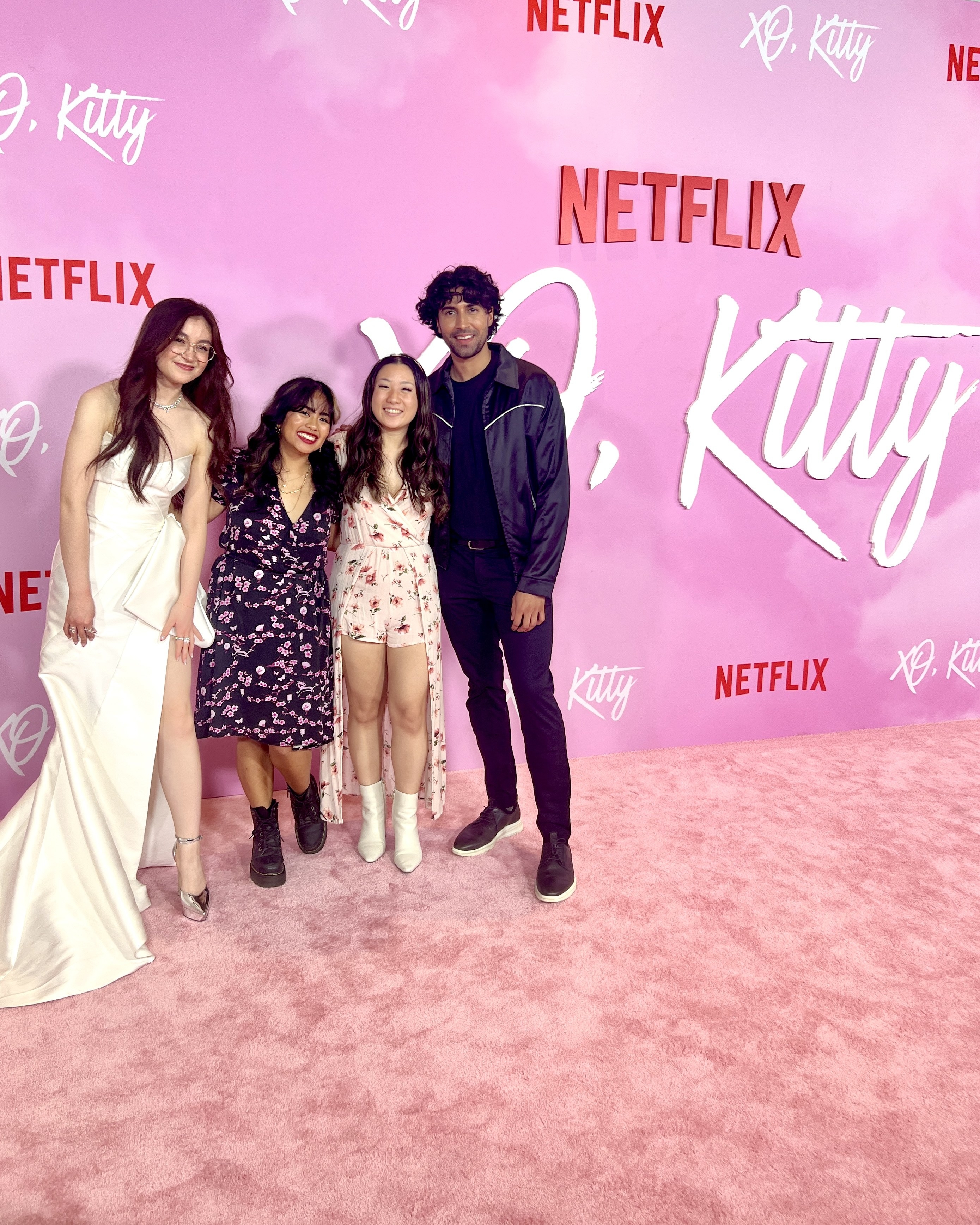 Anna Cathcart, Janna Macatangay, and Rajen Budiyan standing in front of pink XO,  Kitty background and carpet.