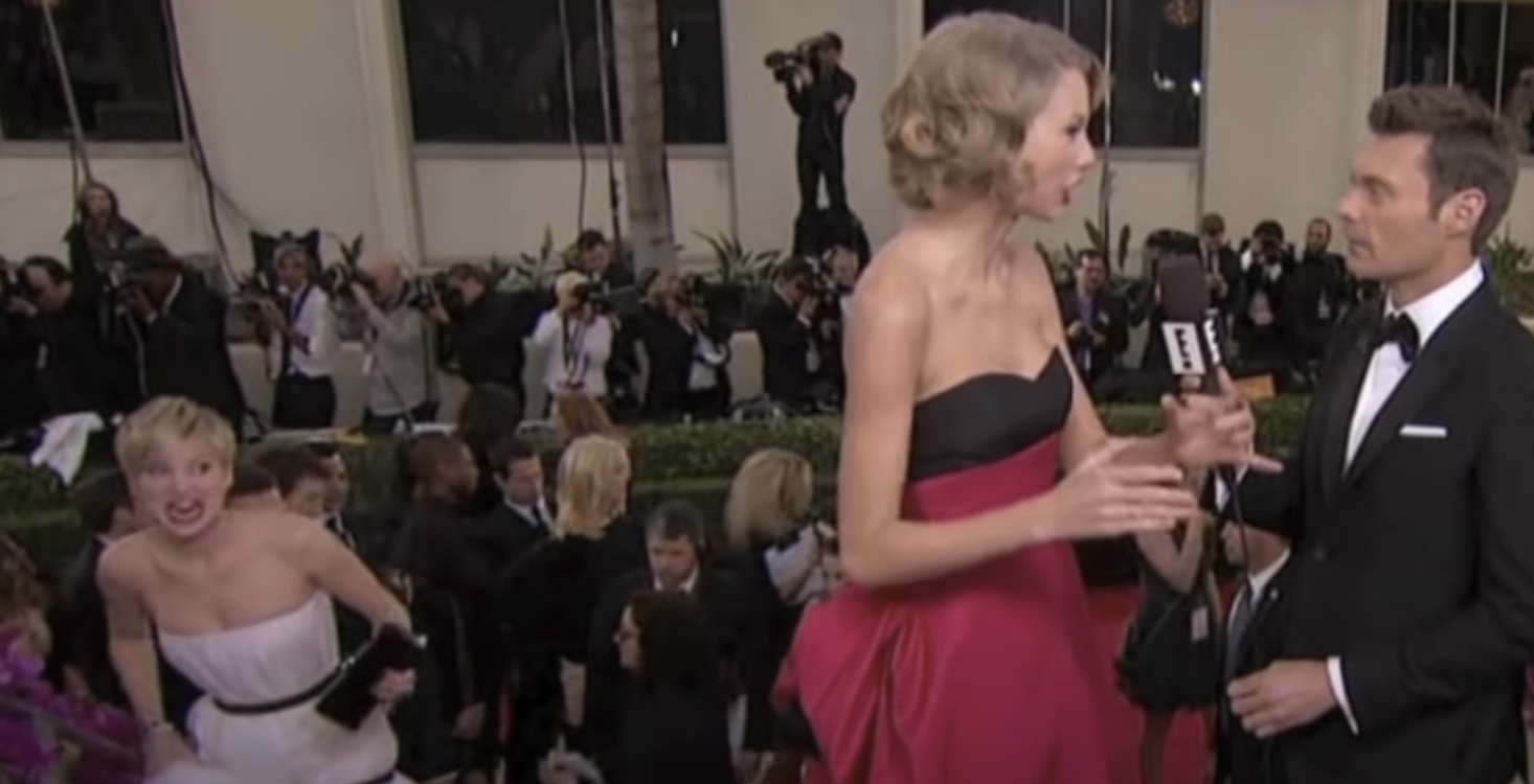 Jennifer in the background making a face during a Taylor interview