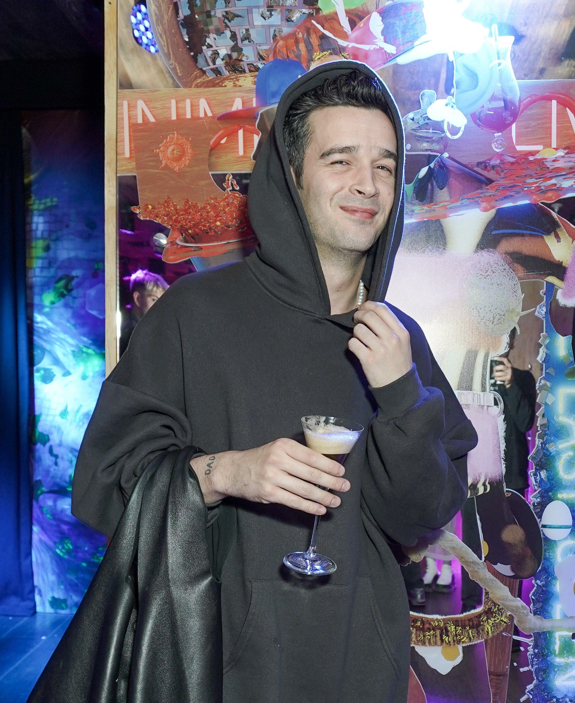 Matty in a hoodie and holding a drink