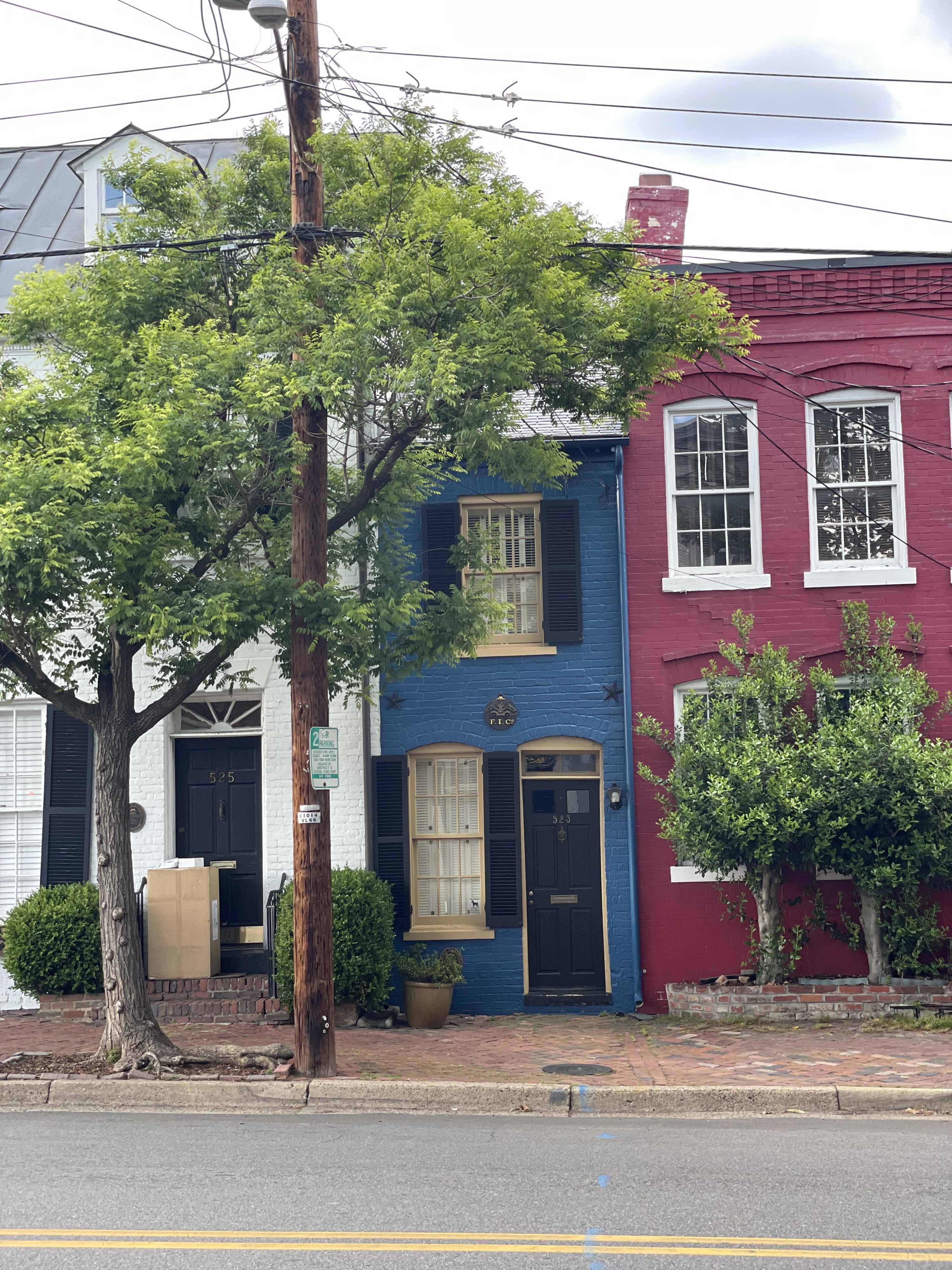 A very narrow, two-story blue house with one window on the second floor and abutting two buildings