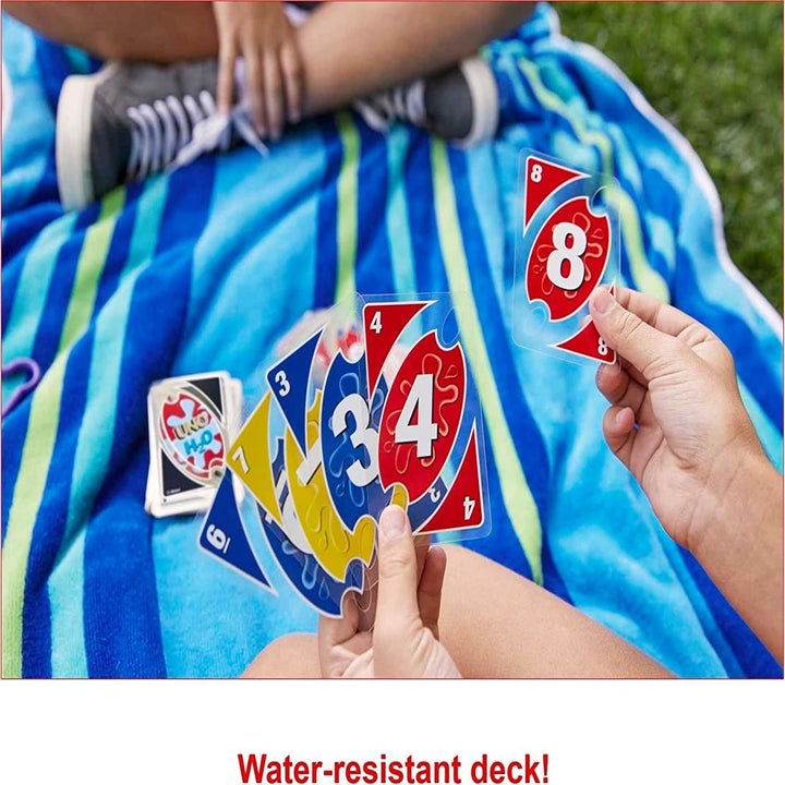 Models sitting outside on a towel holding waterproof playing cards in their hands
