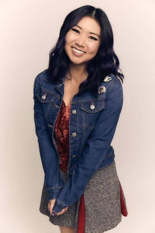 Tricia Fukuhara wearing a jean jacket and a dress