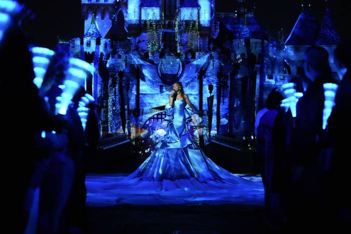 Halle sings in front of the castle at Disneyland which is lit up in blue to look like it's underwater