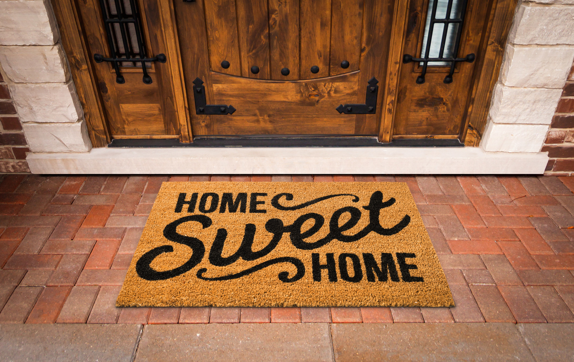 A welcome mat in front of a door reading &quot;home sweet home&quot;