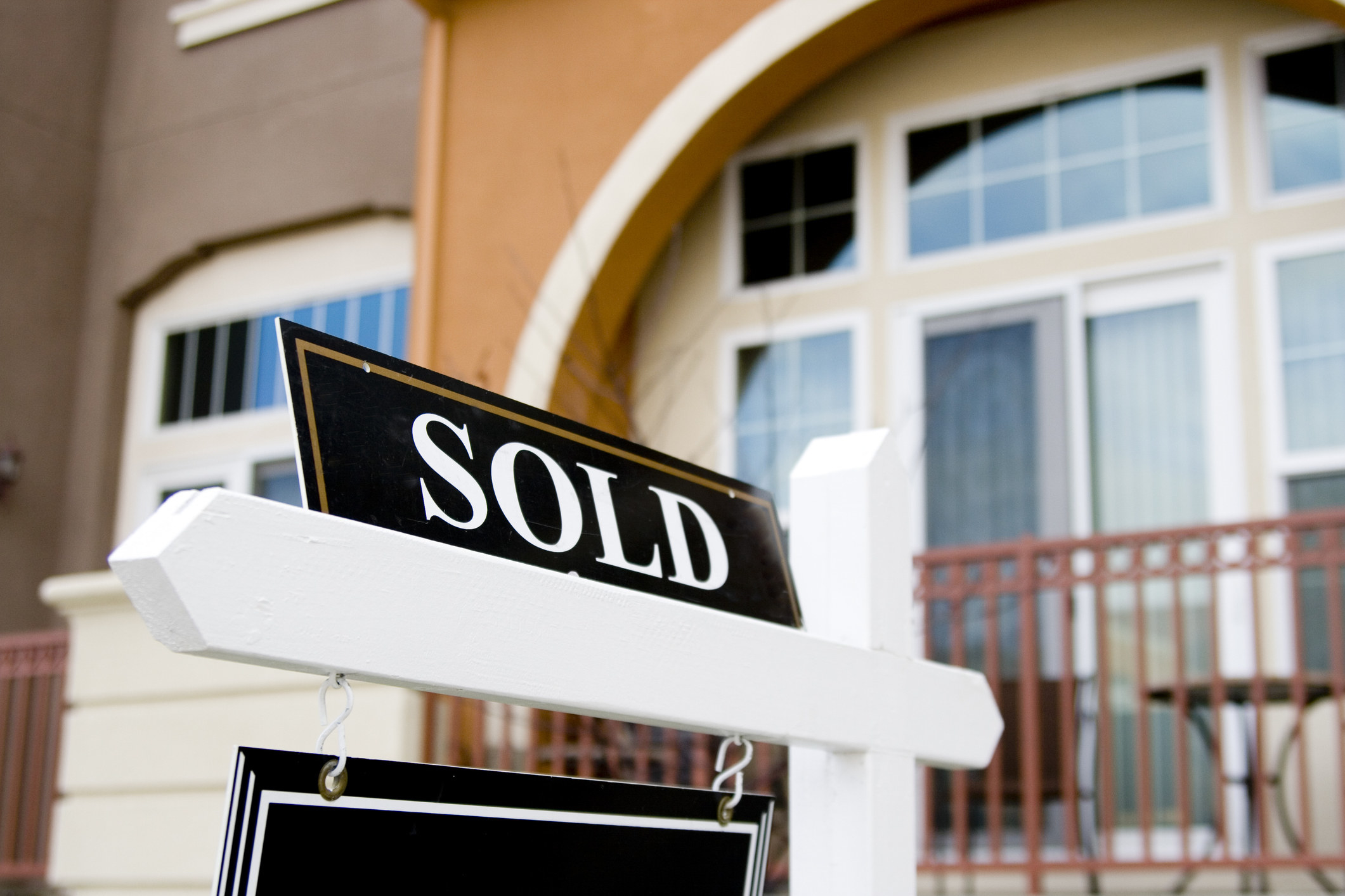A real estate sign reading &quot;sold&quot; outside of a home