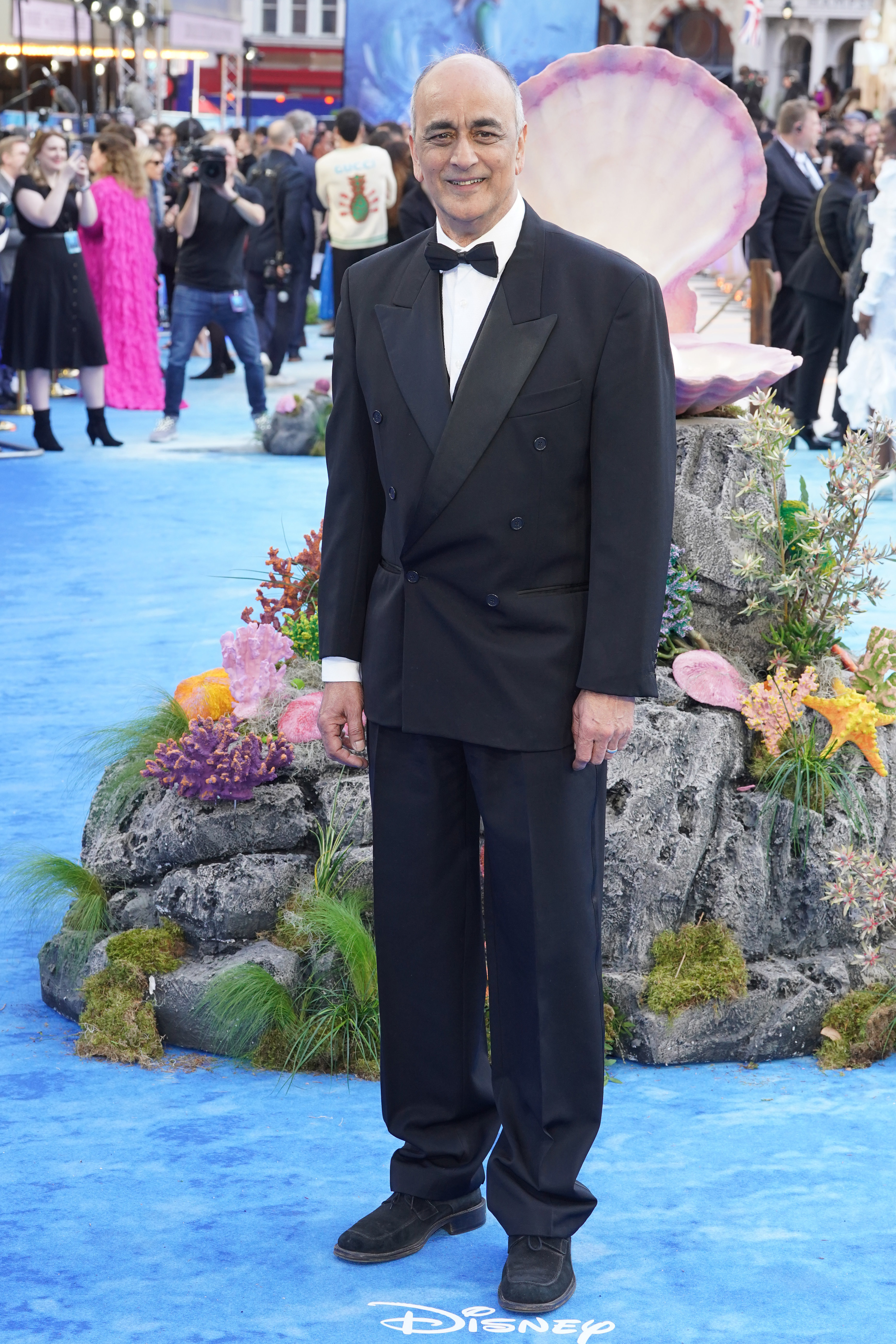 art malik poses on a red carpet